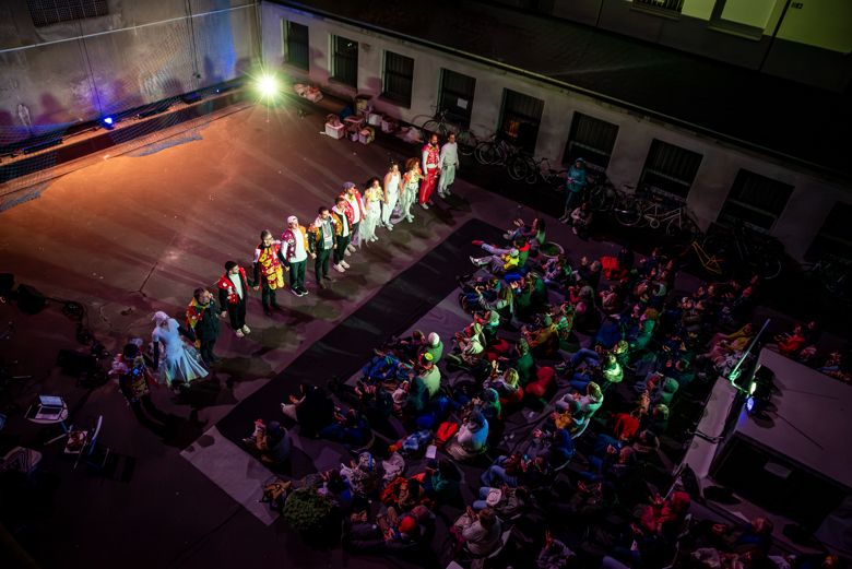 Eco Flight Project cast taking a bow in a Budapest courtyard, seen from above with the audience seated on the ground